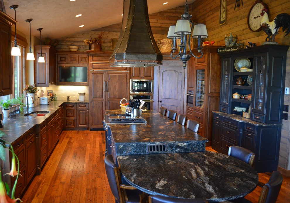 This is an example of a rustic u-shaped kitchen/diner in Minneapolis with a submerged sink, raised-panel cabinets, medium wood cabinets, granite worktops, beige splashback, stone tiled splashback and integrated appliances.