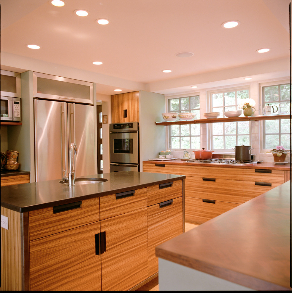 Inredning av ett modernt mellanstort kök, med en undermonterad diskho, släta luckor, skåp i mellenmörkt trä, bänkskiva i kvarts, rostfria vitvaror, ljust trägolv, en köksö och brunt golv