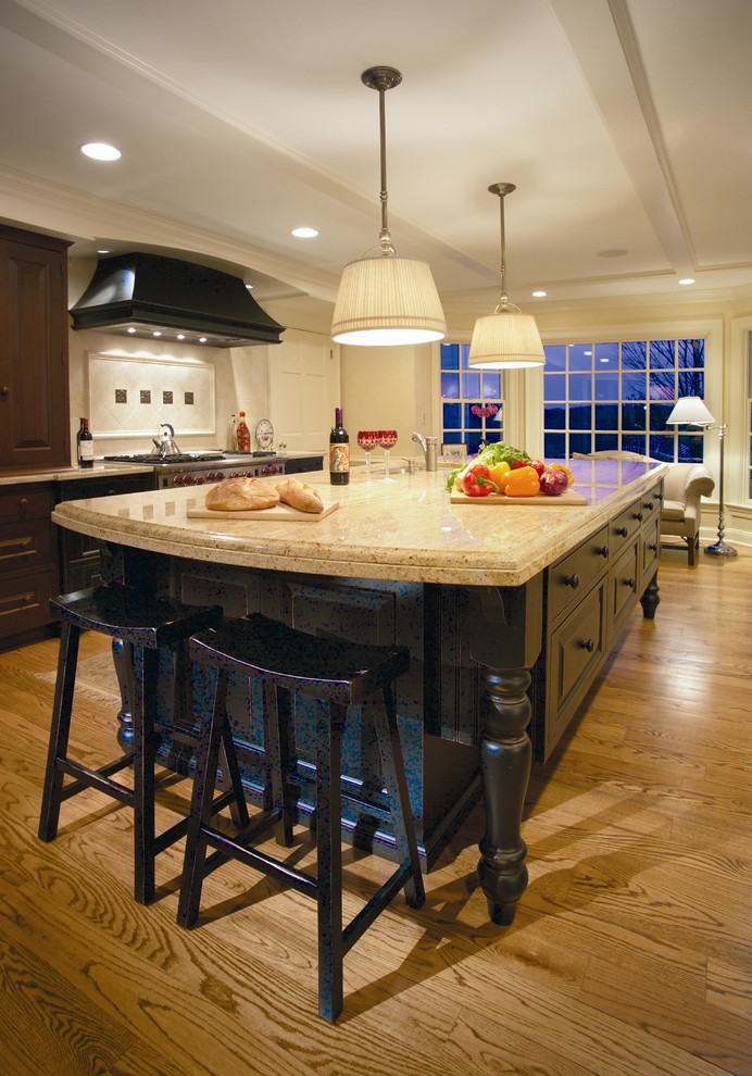 Eat-in kitchen - huge traditional galley medium tone wood floor and brown floor eat-in kitchen idea in Newark with a double-bowl sink, beaded inset cabinets, limestone countertops, beige backsplash, limestone backsplash, stainless steel appliances, an island and black cabinets