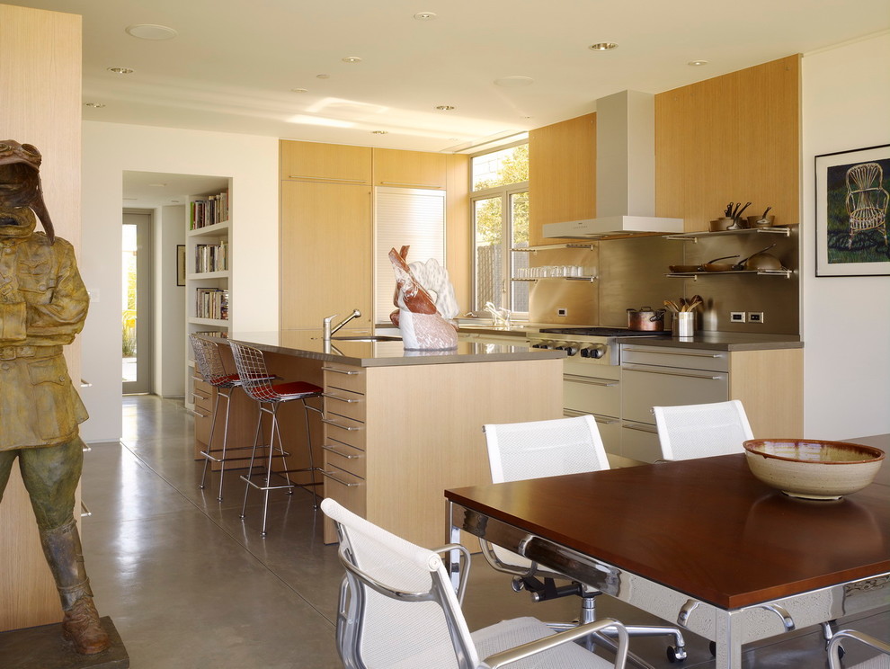 На фото: угловая кухня в стиле модернизм с обеденным столом, врезной мойкой, плоскими фасадами, светлыми деревянными фасадами и фартуком цвета металлик