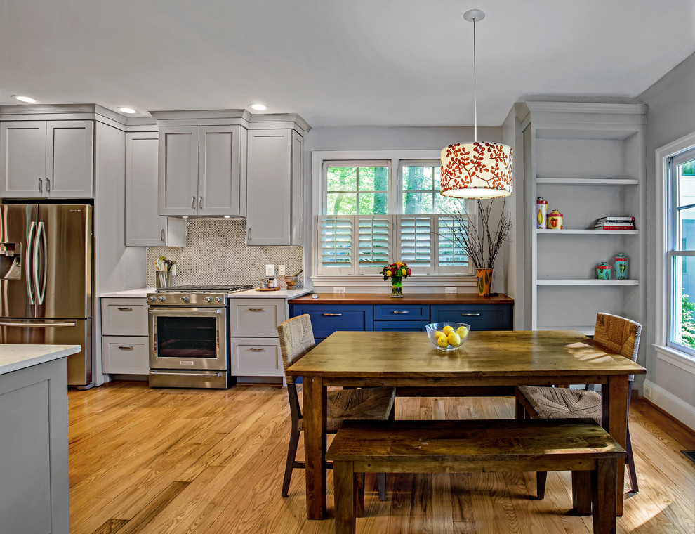 Bild på ett mellanstort lantligt vit vitt kök, med en rustik diskho, skåp i shakerstil, grå skåp, bänkskiva i kvarts, flerfärgad stänkskydd, stänkskydd i glaskakel, rostfria vitvaror, mellanmörkt trägolv och brunt golv