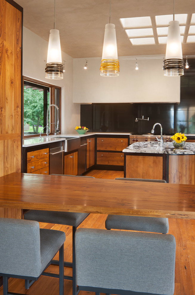 Inspiration for a large zen u-shaped medium tone wood floor and brown floor open concept kitchen remodel in Denver with a farmhouse sink, flat-panel cabinets, medium tone wood cabinets, marble countertops, black backsplash, marble backsplash, stainless steel appliances and two islands