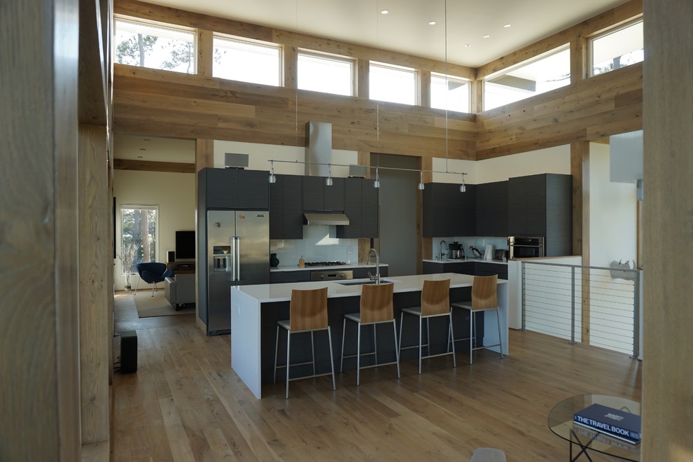 Cette image montre une grande cuisine ouverte design en L avec un placard à porte plane, des portes de placard bleues, un plan de travail en surface solide et îlot.