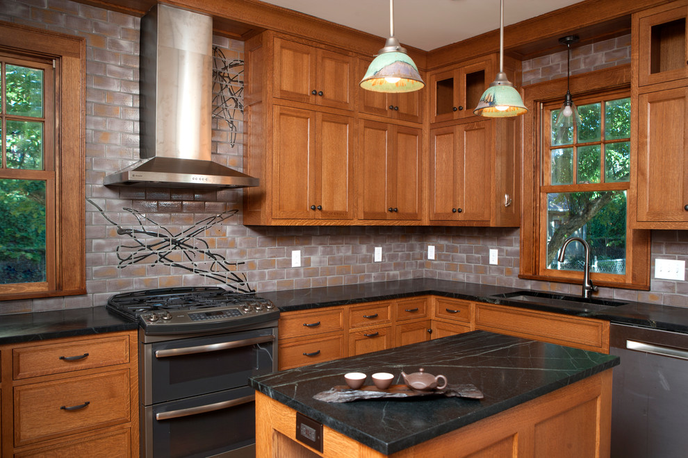 Inredning av ett asiatiskt avskilt, mellanstort l-kök, med en undermonterad diskho, luckor med upphöjd panel, skåp i mellenmörkt trä, bänkskiva i täljsten, grått stänkskydd, stänkskydd i keramik, rostfria vitvaror och en köksö