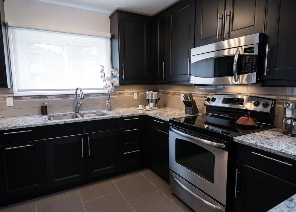 Inspiration for a classic u-shaped kitchen/diner in Ottawa with a submerged sink, shaker cabinets, black cabinets, engineered stone countertops, grey splashback, porcelain splashback and stainless steel appliances.