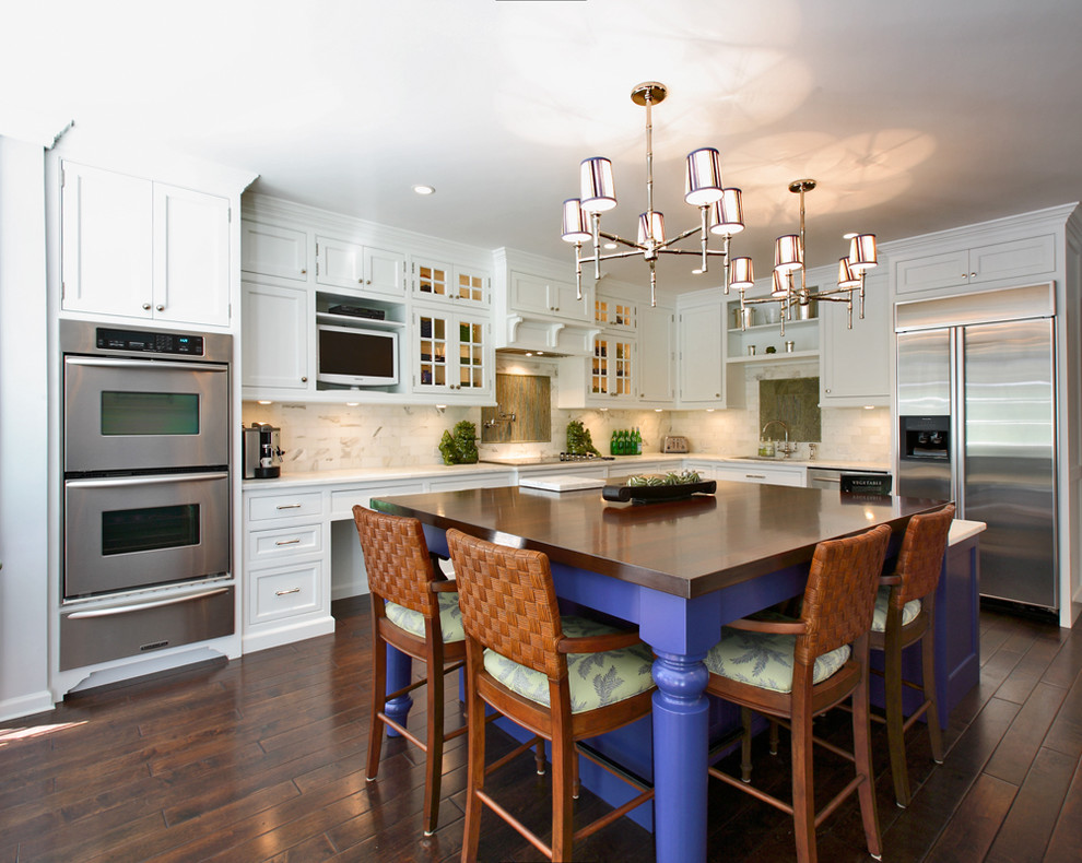 Example of a transitional l-shaped kitchen design in Other with stainless steel appliances, stone tile backsplash, recessed-panel cabinets, white cabinets, white backsplash and wood countertops