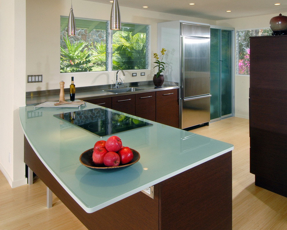 Kitchen - contemporary l-shaped kitchen idea in Hawaii with flat-panel cabinets, stainless steel appliances, an integrated sink, dark wood cabinets, glass countertops and turquoise countertops