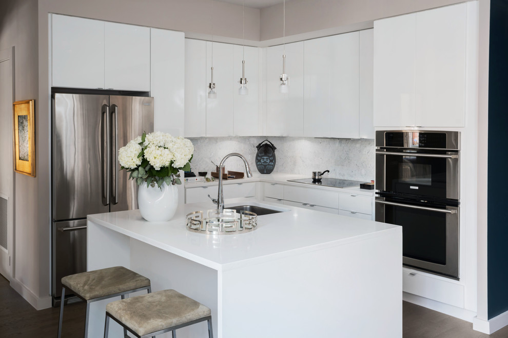 Inspiration for a medium sized modern l-shaped enclosed kitchen in Other with a submerged sink, flat-panel cabinets, white cabinets, engineered stone countertops, white splashback, marble splashback, stainless steel appliances, medium hardwood flooring, an island, brown floors and white worktops.