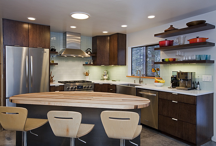 Große Moderne Küche in L-Form mit Landhausspüle, flächenbündigen Schrankfronten, dunklen Holzschränken, Küchenrückwand in Blau, Rückwand aus Glasfliesen, Küchengeräten aus Edelstahl, Kücheninsel und braunem Boden in Oklahoma City