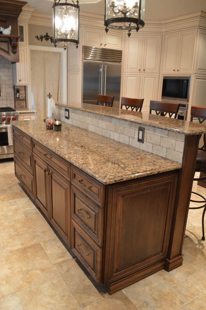 Eat-in kitchen - large traditional u-shaped ceramic tile eat-in kitchen idea in Newark with a farmhouse sink, raised-panel cabinets, dark wood cabinets, quartz countertops, beige backsplash, stone tile backsplash, stainless steel appliances and an island