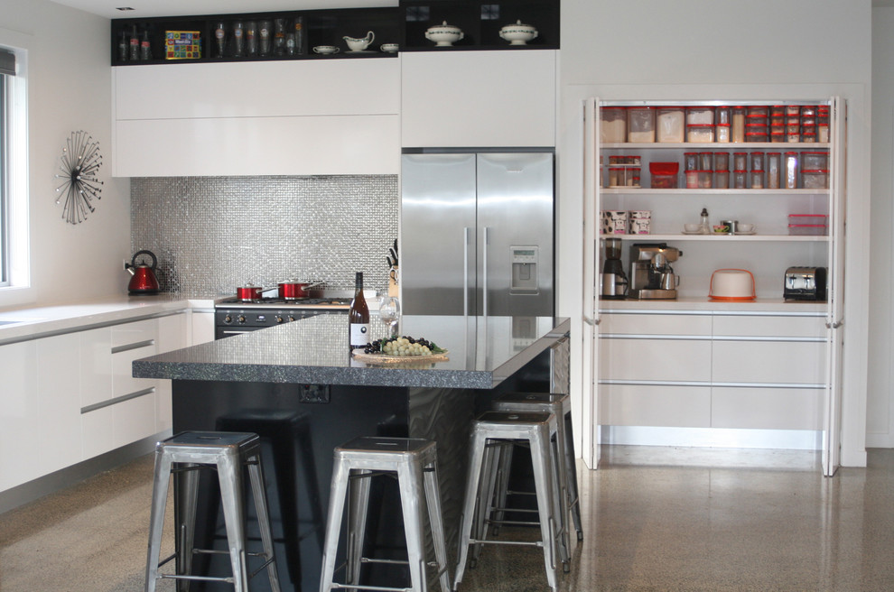 Inspiration för ett mellanstort funkis kök och matrum, med en enkel diskho, vita skåp, bänkskiva i kvarts, stänkskydd med metallisk yta, betonggolv och en köksö