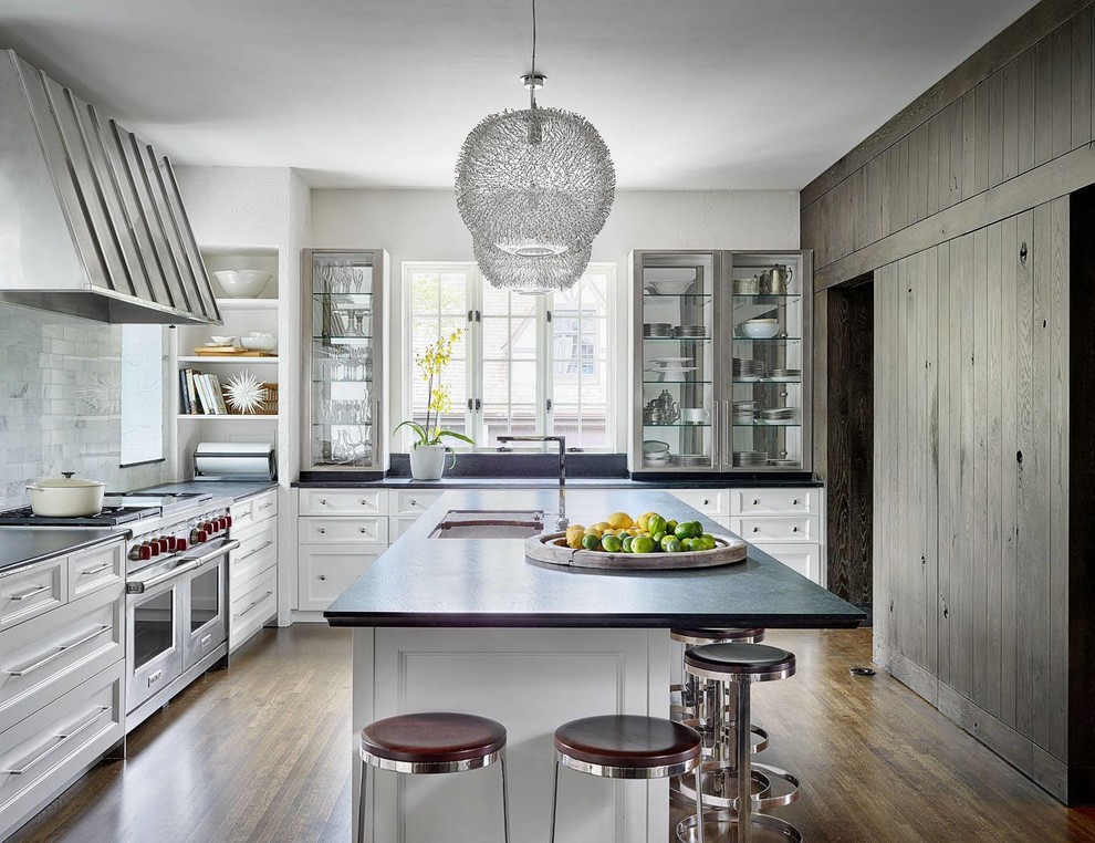 Inspiration for a classic kitchen in Chicago with a submerged sink, glass-front cabinets, white splashback, stainless steel appliances, dark hardwood flooring and an island.