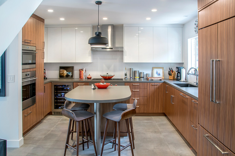 Immagine di una cucina design con lavello sottopiano, ante lisce, ante in legno scuro, paraspruzzi bianco, elettrodomestici in acciaio inossidabile, pavimento beige e top grigio