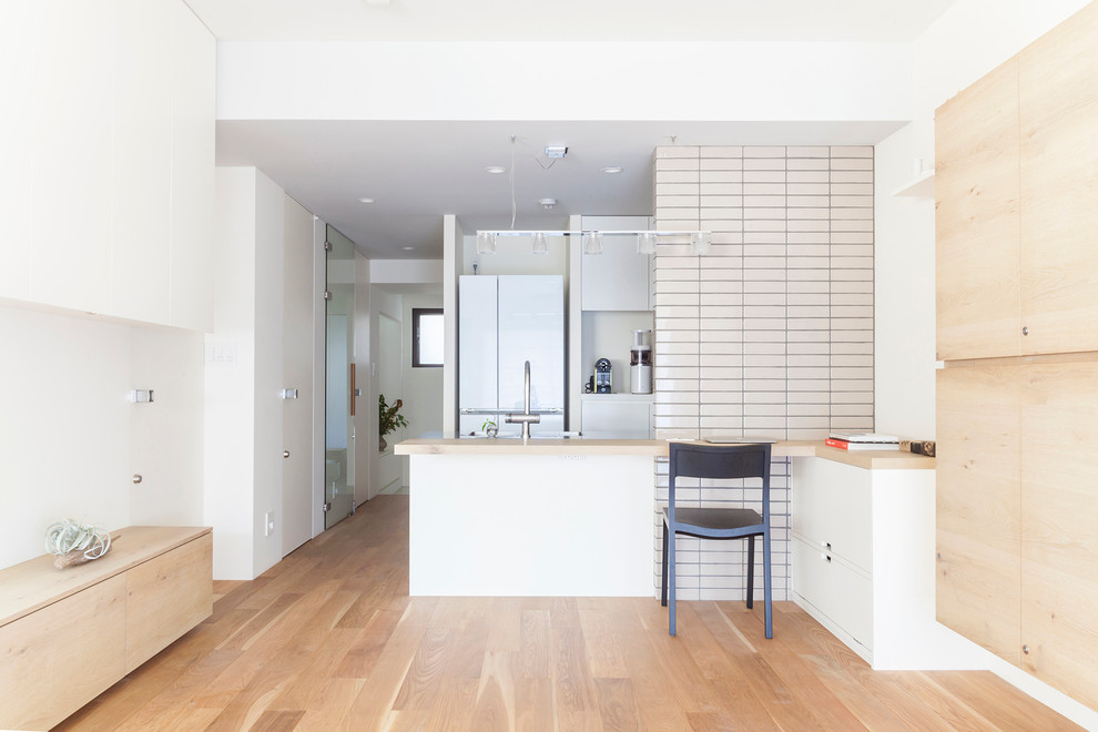 東京23区にあるおしゃれなキッチン (フラットパネル扉のキャビネット、白いキャビネット、白い調理設備、無垢フローリング) の写真