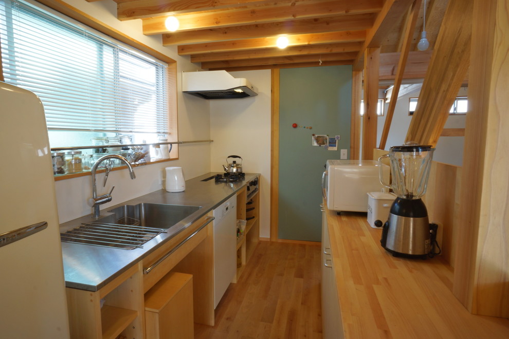 Medium sized scandinavian galley enclosed kitchen in Other with stainless steel worktops, white appliances and light hardwood flooring.