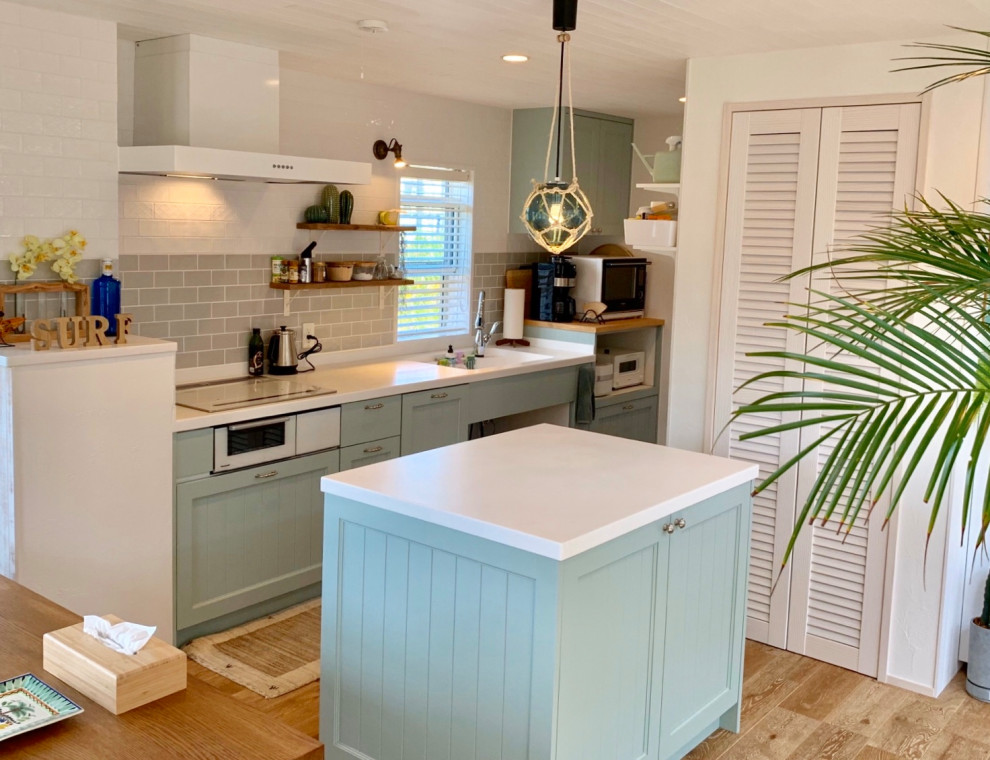 Kitchen - large tropical single-wall kitchen idea in Other with an undermount sink, recessed-panel cabinets, green cabinets, solid surface countertops, white appliances, an island and white countertops