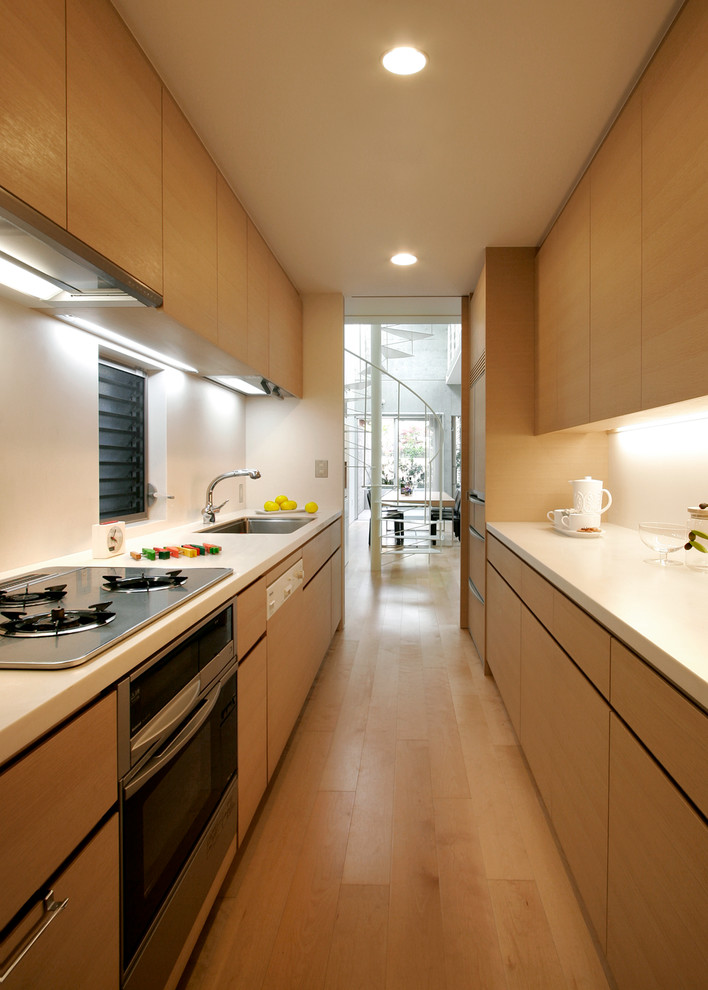Свежая идея для дизайна: отдельная, прямая кухня в стиле модернизм с одинарной мойкой, плоскими фасадами, фасадами цвета дерева среднего тона, паркетным полом среднего тона, полуостровом, коричневым полом и белой столешницей - отличное фото интерьера