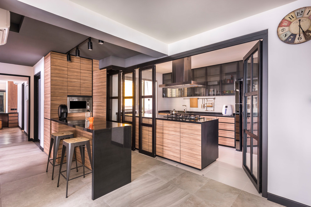 Imagen de cocina contemporánea con armarios con paneles lisos, puertas de armario de madera clara, electrodomésticos negros, suelo beige y encimeras negras