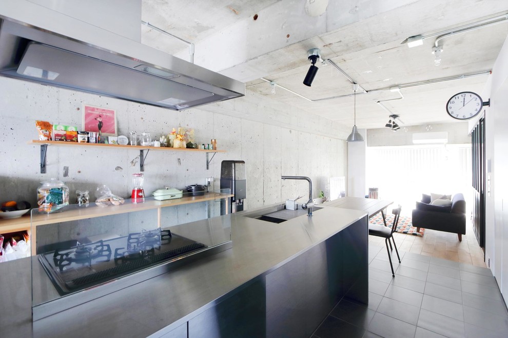 Foto på ett industriellt linjärt kök med öppen planlösning, med en enkel diskho, bänkskiva i rostfritt stål, en halv köksö och grått golv