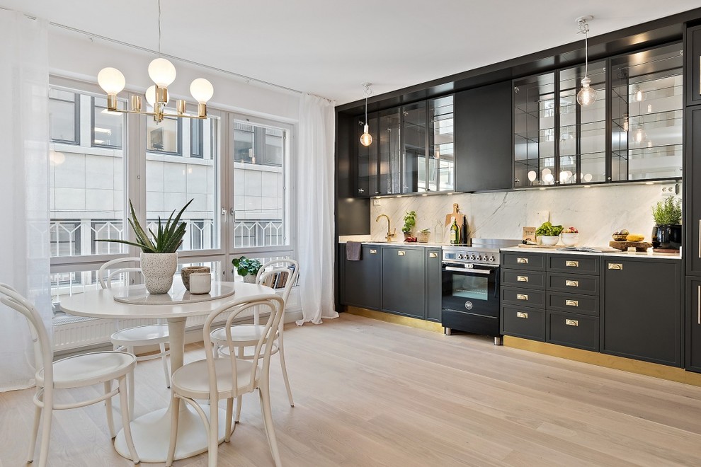 Idéer för att renovera ett mellanstort minimalistiskt linjärt kök och matrum, med luckor med profilerade fronter, svarta skåp, marmorbänkskiva, rostfria vitvaror och ljust trägolv