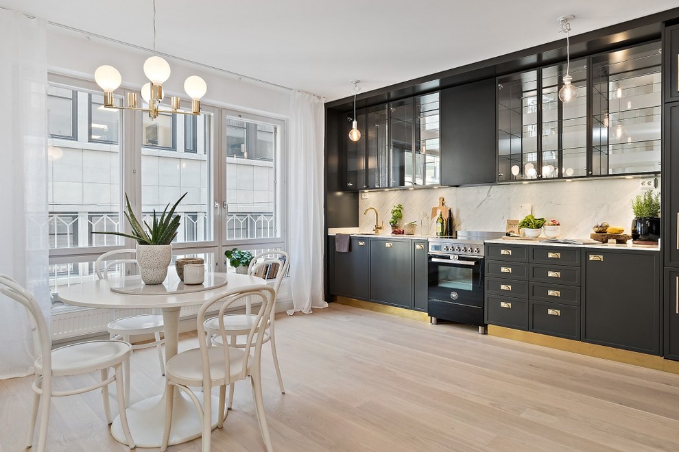 Example of a mid-sized danish single-wall light wood floor eat-in kitchen design in Stockholm with beaded inset cabinets, black cabinets, marble countertops, stainless steel appliances and no island