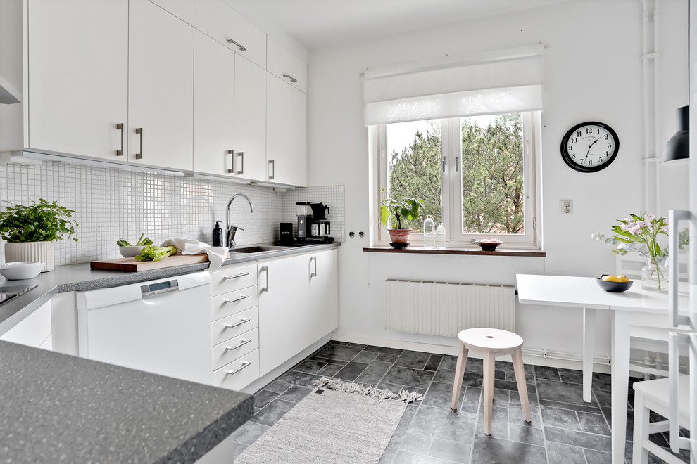 Cette photo montre une cuisine américaine scandinave avec un placard à porte plane, des portes de placard blanches, une crédence blanche, sol en stratifié, aucun îlot, un sol gris et un électroménager blanc.
