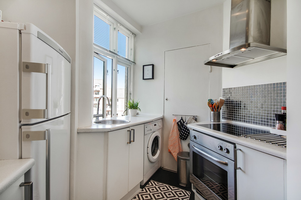 Kleine Nordische Küche ohne Insel mit Waschbecken, flächenbündigen Schrankfronten, Küchenrückwand in Schwarz und Küchengeräten aus Edelstahl in Kopenhagen