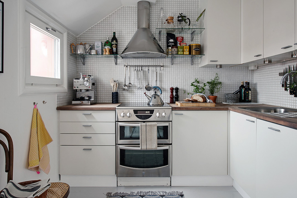 Design ideas for a large scandi l-shaped enclosed kitchen in Gothenburg with a single-bowl sink, flat-panel cabinets, white cabinets, wood worktops, stainless steel appliances, painted wood flooring and no island.