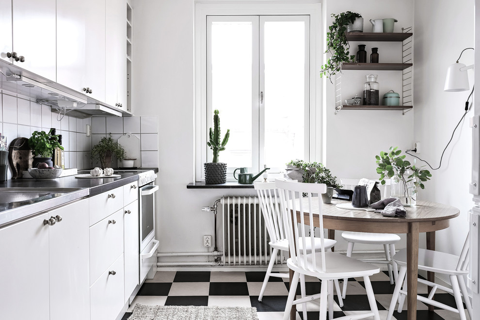Idéer för att renovera ett mellanstort skandinaviskt linjärt kök och matrum, med släta luckor, vita skåp, bänkskiva i rostfritt stål, vitt stänkskydd, vita vitvaror, linoleumgolv och flerfärgat golv