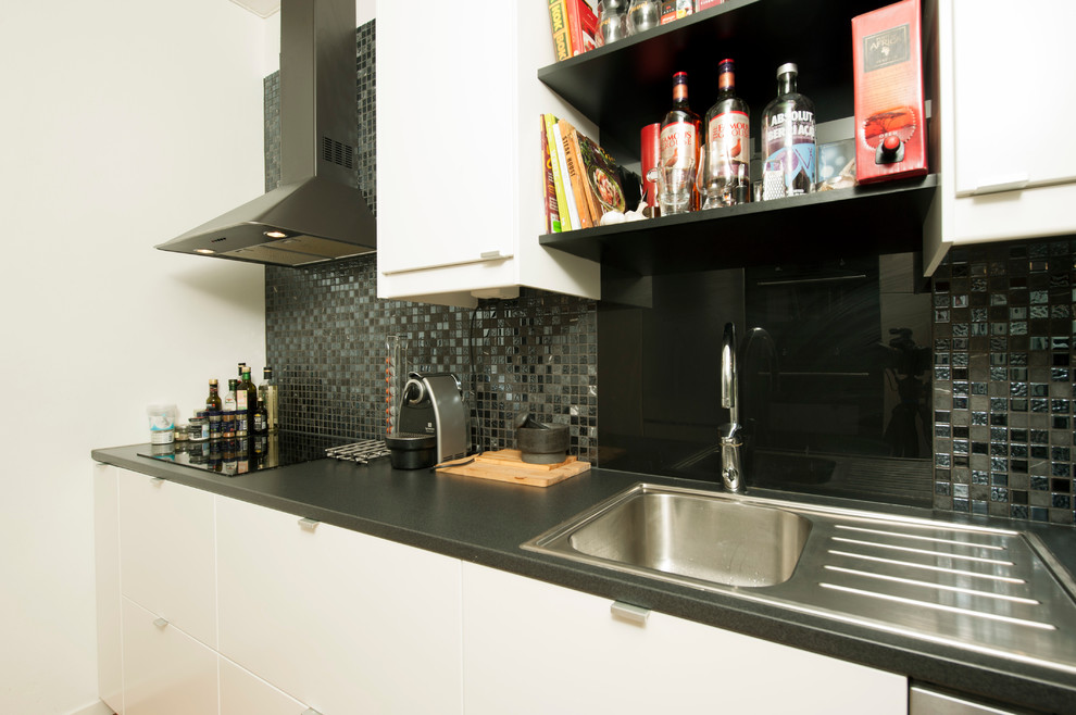 Imagen de cocina lineal contemporánea pequeña cerrada con puertas de armario blancas y electrodomésticos negros