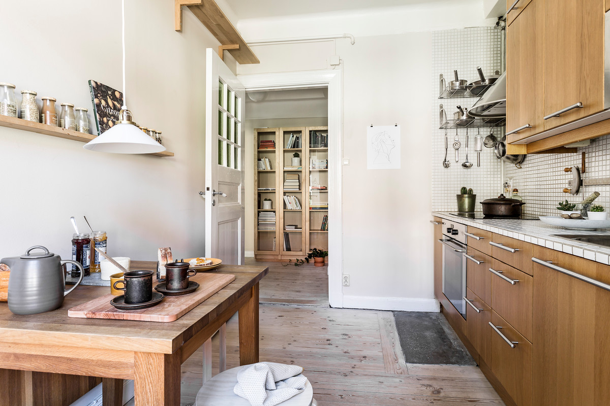 ストックホルムにある小さなラスティックスタイルのおしゃれなキッチン (フラットパネル扉のキャビネット、中間色木目調キャビネット、淡色無垢フローリング、アイランドなし) の写真