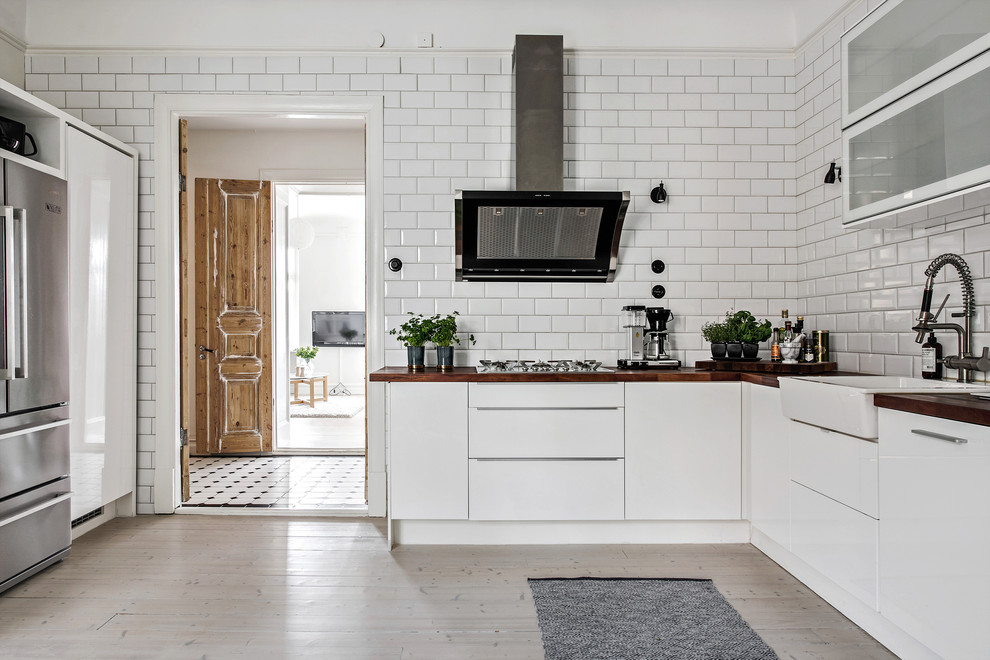 Idéer för att renovera ett stort minimalistiskt linjärt kök och matrum, med en rustik diskho, släta luckor, vita skåp, träbänkskiva, vitt stänkskydd, stänkskydd i porslinskakel, rostfria vitvaror och ljust trägolv