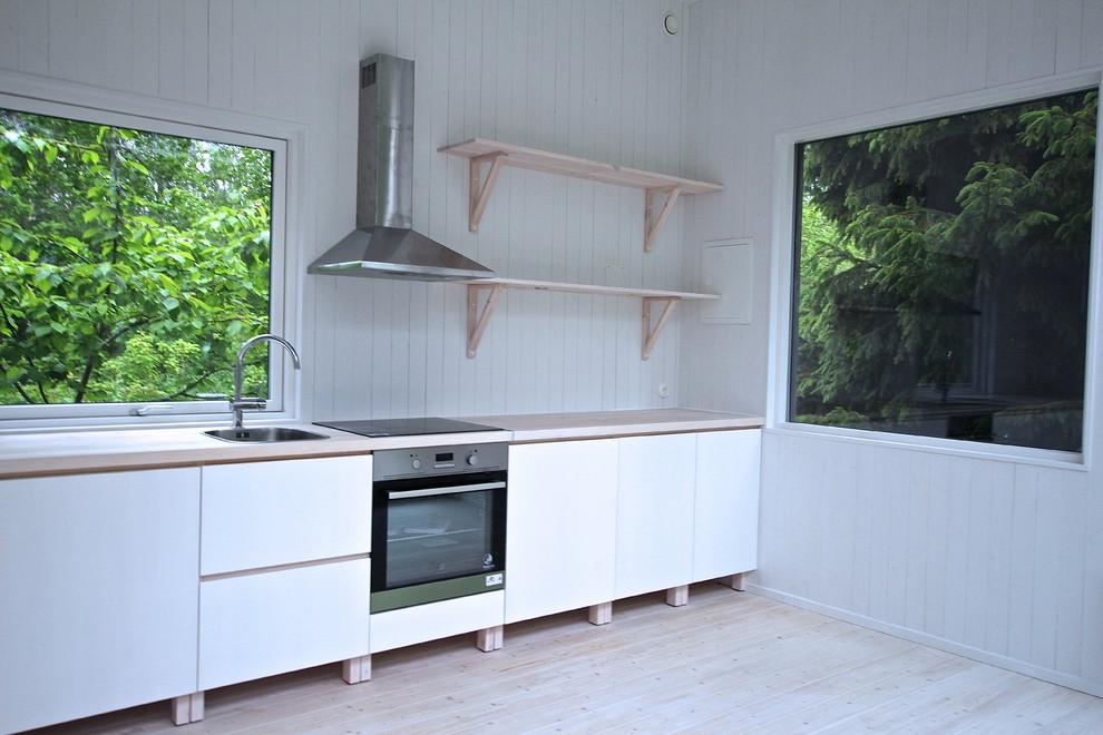 Стильный дизайн: маленькая прямая кухня-гостиная в скандинавском стиле с монолитной мойкой, открытыми фасадами, светлыми деревянными фасадами, деревянной столешницей, белым фартуком, фартуком из стекла, белой техникой и светлым паркетным полом для на участке и в саду - последний тренд