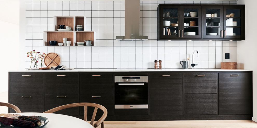 Inspiration for a medium sized scandi single-wall kitchen/diner in Malmo with a submerged sink, flat-panel cabinets, brown cabinets, laminate countertops, white splashback, porcelain splashback and black appliances.