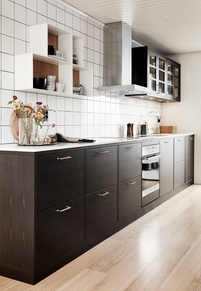 Inredning av ett nordiskt mellanstort linjärt kök och matrum, med en undermonterad diskho, släta luckor, bruna skåp, laminatbänkskiva, vitt stänkskydd, stänkskydd i porslinskakel och svarta vitvaror