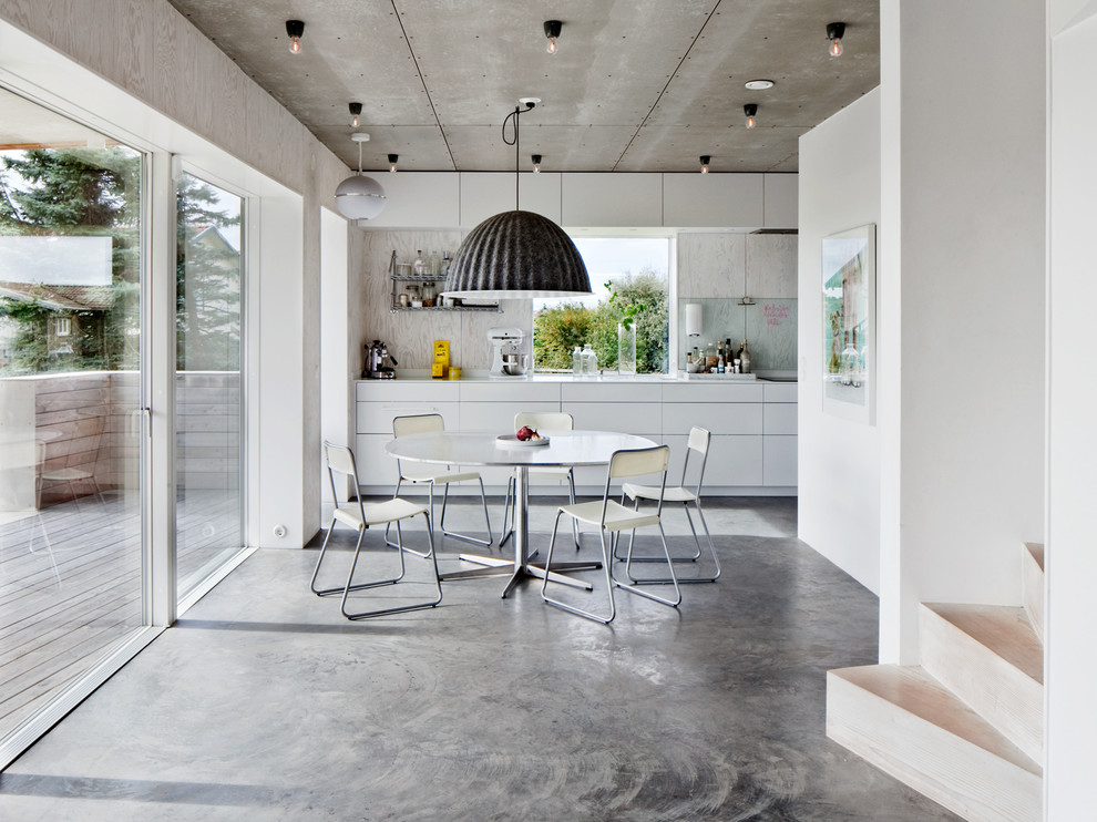 ヨーテボリにある高級な広いコンテンポラリースタイルのおしゃれなキッチン (フラットパネル扉のキャビネット、白いキャビネット、アイランドなし、コンクリートの床) の写真