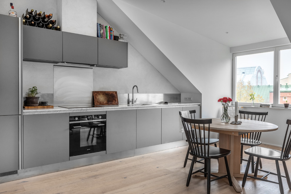 Danish single-wall light wood floor eat-in kitchen photo in Stockholm with an undermount sink, flat-panel cabinets, gray cabinets, marble countertops, metallic backsplash, black appliances, no island and white countertops