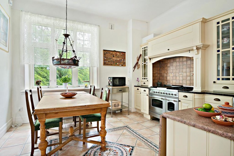 Eat-in kitchen - mid-sized farmhouse l-shaped ceramic tile eat-in kitchen idea in Stockholm with recessed-panel cabinets, yellow cabinets, wood countertops, brown backsplash, ceramic backsplash, stainless steel appliances and no island
