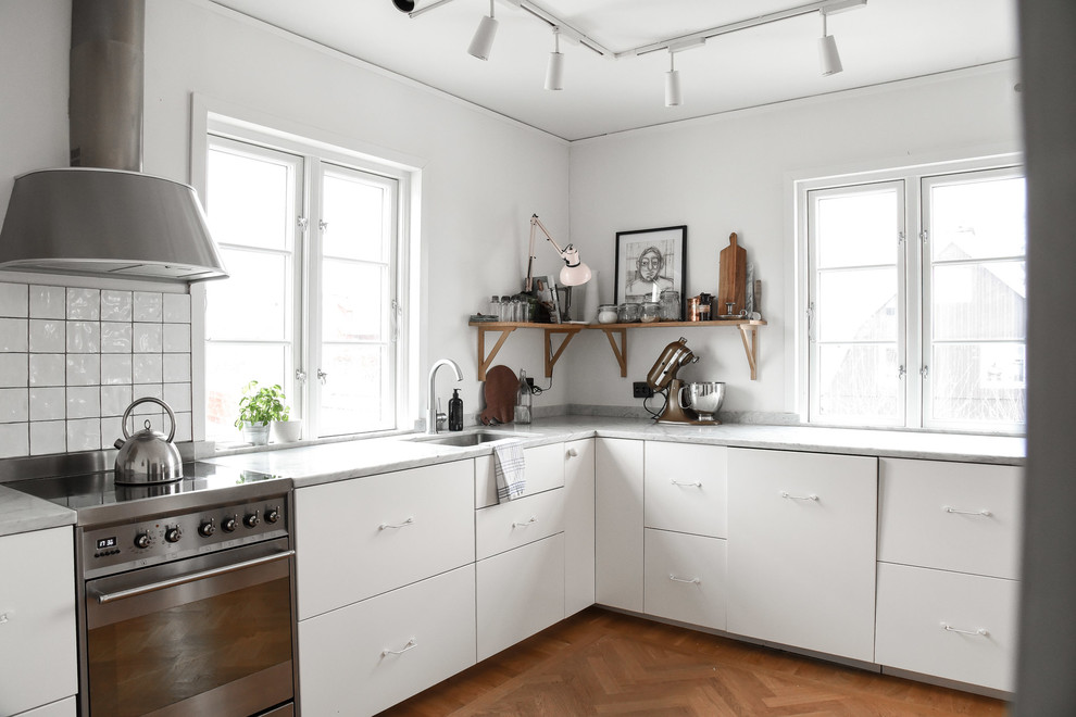 Inspiration för avskilda skandinaviska grått l-kök, med släta luckor, vita skåp, mellanmörkt trägolv, brunt golv, en undermonterad diskho, vitt stänkskydd och rostfria vitvaror