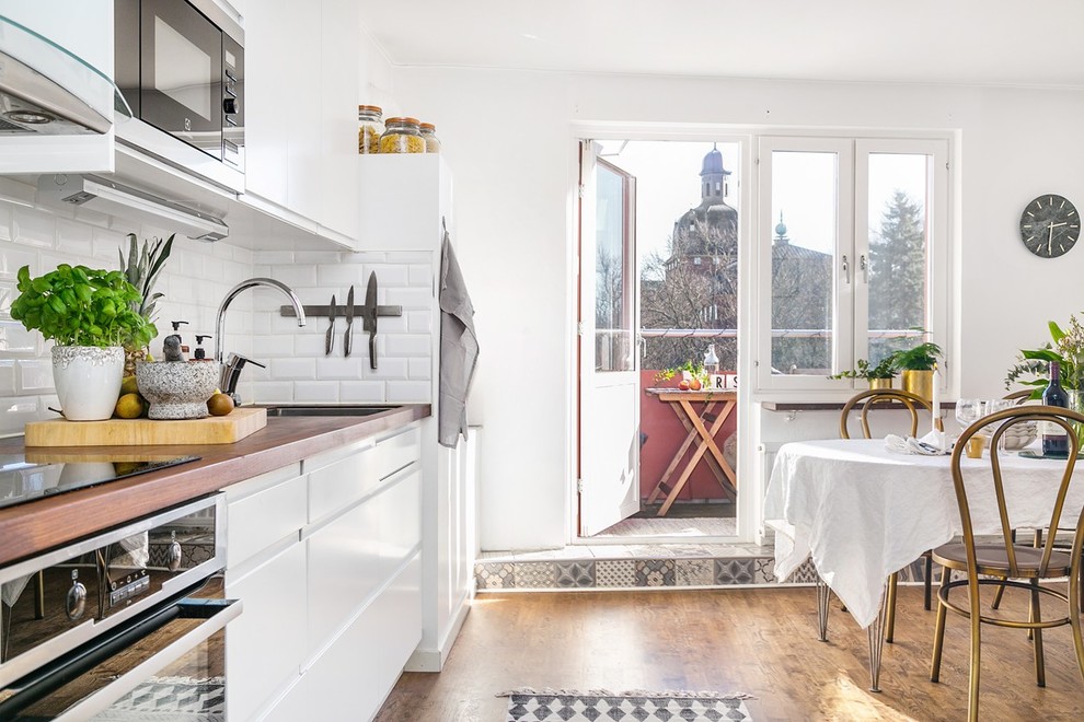 Idéer för ett mellanstort skandinaviskt kök och matrum, med träbänkskiva, integrerade vitvaror och brunt golv