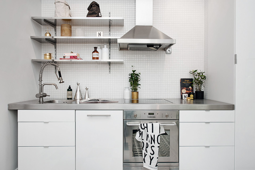 Inredning av ett skandinaviskt avskilt, litet linjärt kök, med en enkel diskho, släta luckor, vita skåp, bänkskiva i rostfritt stål och rostfria vitvaror