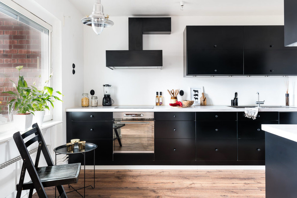 Zweizeilige, Mittelgroße Moderne Küche mit flächenbündigen Schrankfronten, schwarzen Schränken, Küchengeräten aus Edelstahl, hellem Holzboden, Kücheninsel, Waschbecken und Marmor-Arbeitsplatte in Örebro