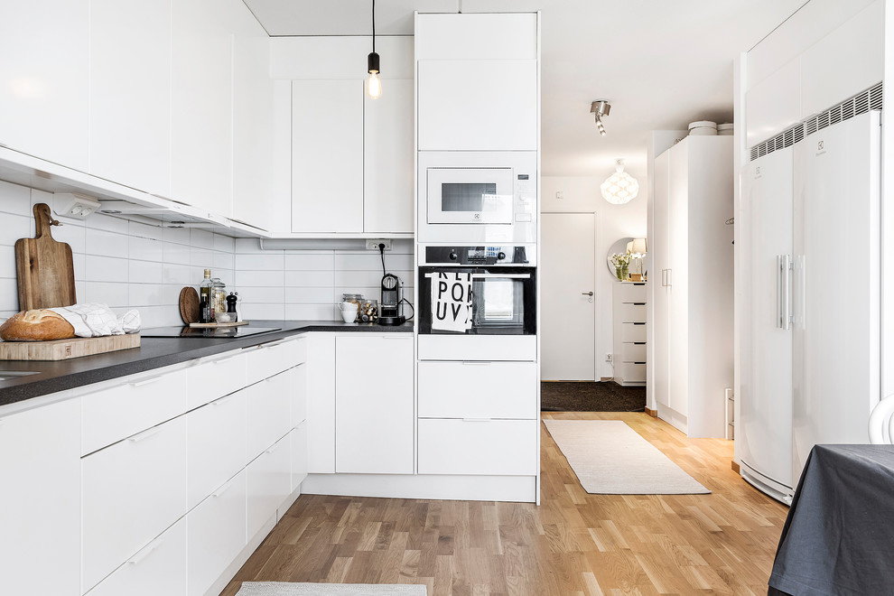 Esempio di una cucina scandinava di medie dimensioni con ante lisce, ante bianche, paraspruzzi bianco, parquet chiaro e nessuna isola