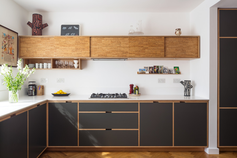 Inspiration for a scandinavian l-shaped kitchen in London with flat-panel cabinets, black cabinets, white splashback, medium hardwood flooring, no island and white worktops.