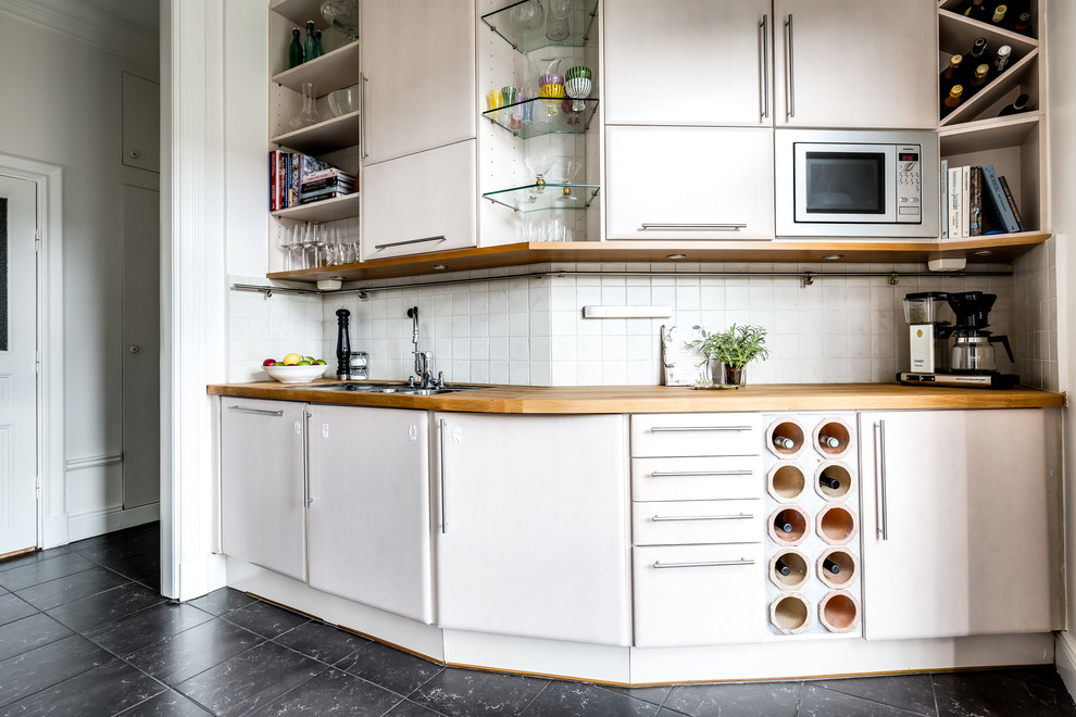 Modelo de cocina escandinava de tamaño medio sin isla con armarios con paneles lisos, puertas de armario blancas, encimera de madera y salpicadero blanco