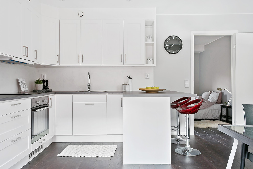 Idéer för mellanstora nordiska kök, med luckor med infälld panel, vita skåp, mörkt trägolv och en halv köksö