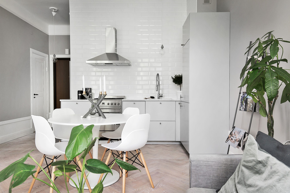 Mid-sized danish l-shaped light wood floor eat-in kitchen photo in Stockholm with an undermount sink, flat-panel cabinets, gray cabinets, white backsplash, subway tile backsplash, stainless steel appliances and no island
