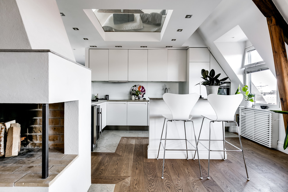 Immagine di una piccola cucina nordica con ante lisce, ante bianche, elettrodomestici in acciaio inossidabile, pavimento in legno massello medio, pavimento marrone e top grigio