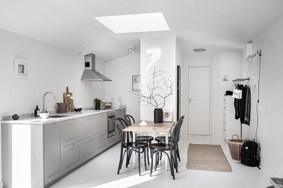 Minimalistisk inredning av ett mellanstort linjärt kök, med en enkel diskho, luckor med infälld panel, grå skåp, marmorbänkskiva, målat trägolv och rostfria vitvaror