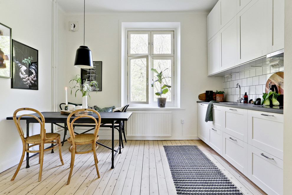 Idéer för att renovera ett skandinaviskt grå linjärt grått kök och matrum, med skåp i shakerstil, vita skåp, vitt stänkskydd, ljust trägolv och beiget golv